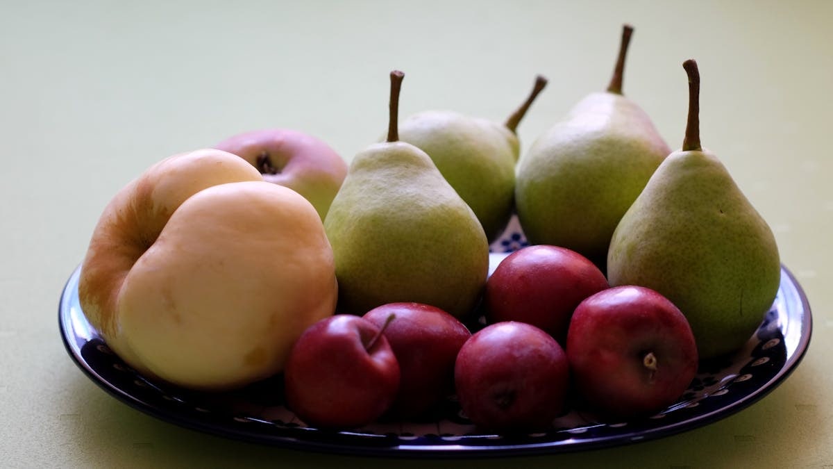 A colorful assortment of apples and pears elegantly displayed on a patterned plate.
